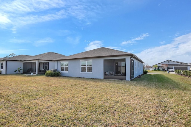 rear view of house featuring a sunroom and a lawn