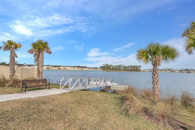 view of dock with a yard and a water view