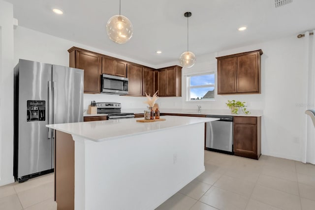 kitchen featuring appliances with stainless steel finishes, pendant lighting, sink, a center island, and dark brown cabinetry