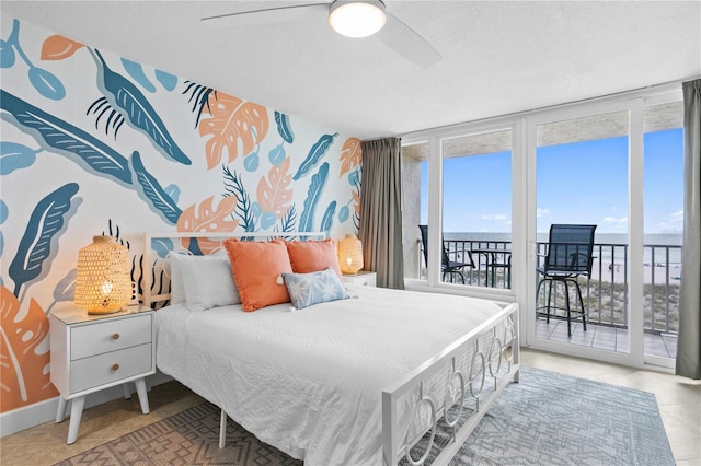 bedroom featuring tile patterned flooring, access to exterior, ceiling fan, floor to ceiling windows, and a water view