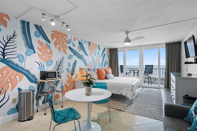 tiled bedroom with a textured ceiling, access to outside, expansive windows, and ceiling fan