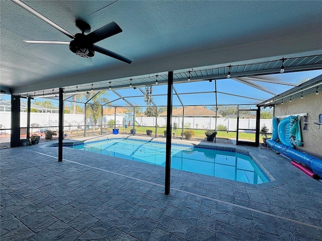 view of swimming pool featuring a patio area, ceiling fan, and glass enclosure