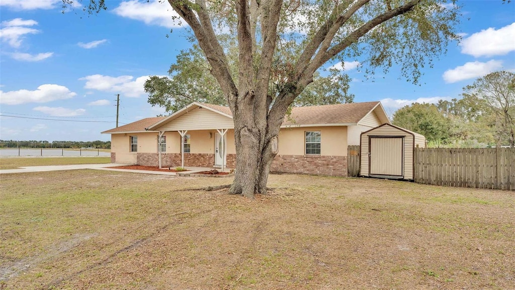 ranch-style house featuring a storage unit and a front lawn