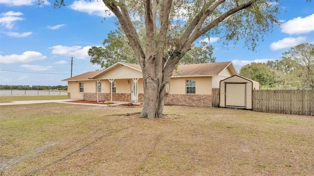 ranch-style house featuring a storage unit and a front lawn