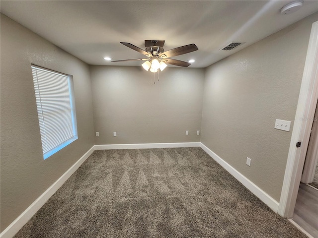 spare room featuring visible vents, a ceiling fan, carpet floors, baseboards, and a textured wall