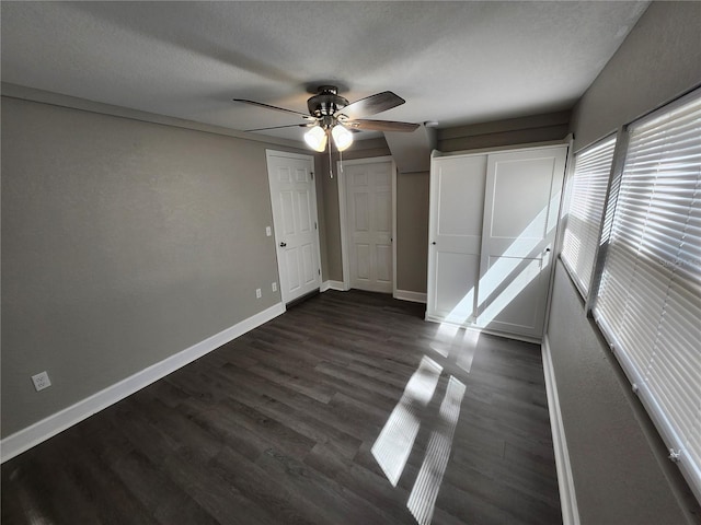 unfurnished bedroom featuring dark wood-type flooring, a ceiling fan, baseboards, and a textured ceiling