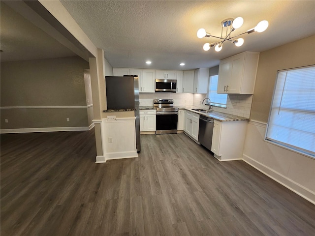 kitchen with dark wood finished floors, a sink, white cabinets, appliances with stainless steel finishes, and backsplash