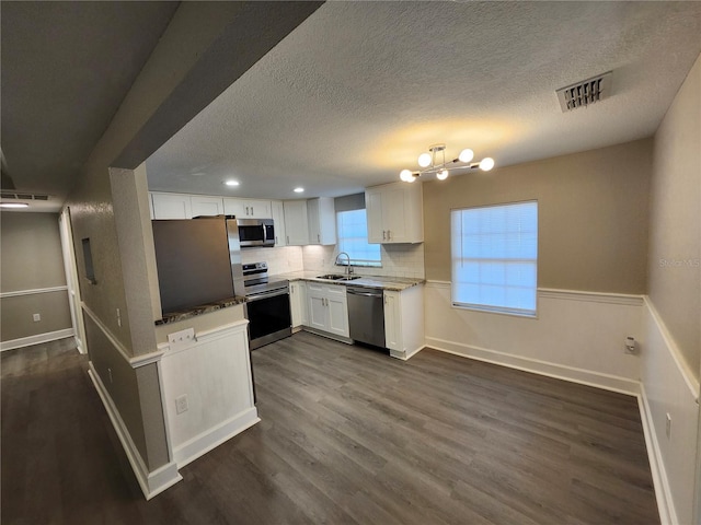 kitchen featuring visible vents, dark wood finished floors, white cabinets, stainless steel appliances, and a sink