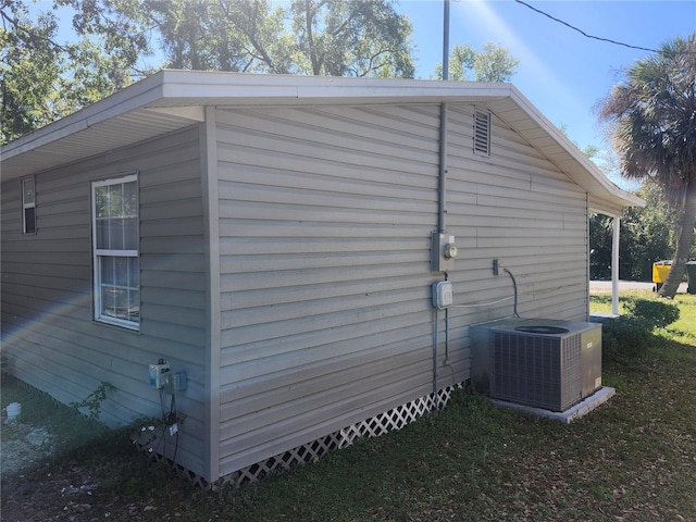 view of side of home featuring central AC unit and a lawn