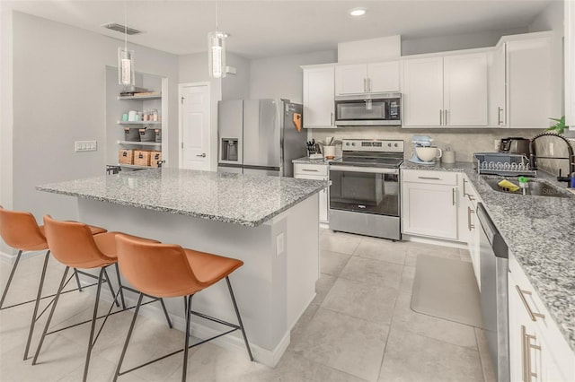 kitchen featuring stainless steel appliances, sink, white cabinets, a kitchen breakfast bar, and a kitchen island