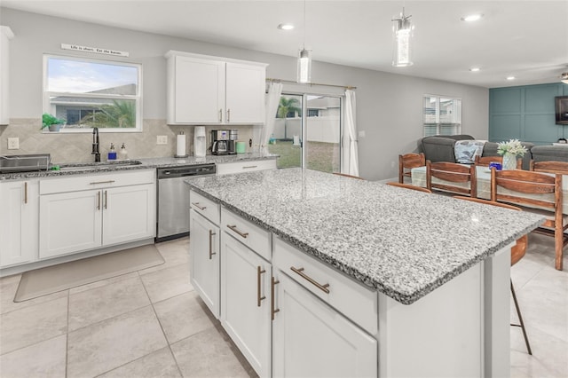 kitchen with white cabinets, a center island, sink, decorative light fixtures, and stainless steel dishwasher