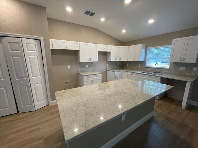 kitchen with sink, white cabinetry, a center island, and light stone counters