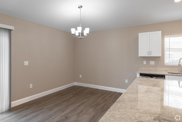 kitchen with white cabinets, dishwasher, pendant lighting, light stone counters, and sink