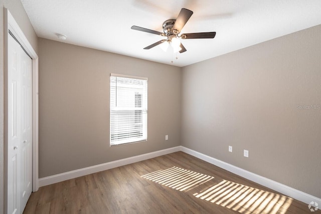 unfurnished bedroom featuring ceiling fan, a closet, and wood-type flooring