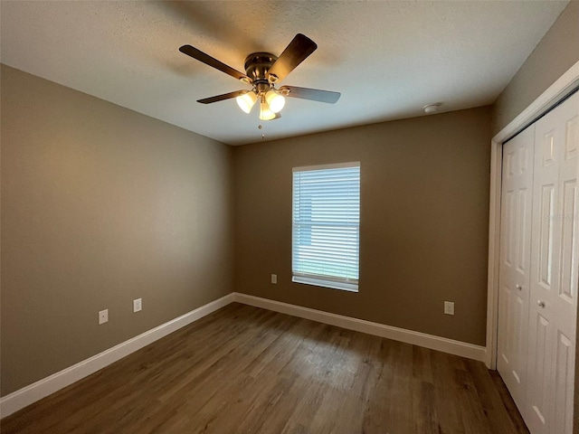 unfurnished bedroom with dark wood-type flooring, ceiling fan, and a closet