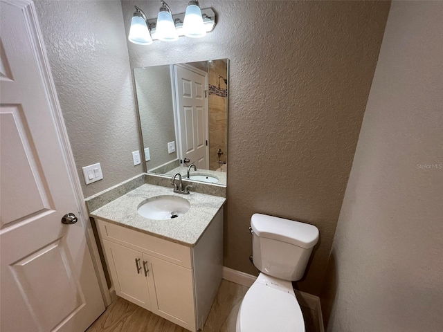 bathroom with wood-type flooring, vanity, and toilet