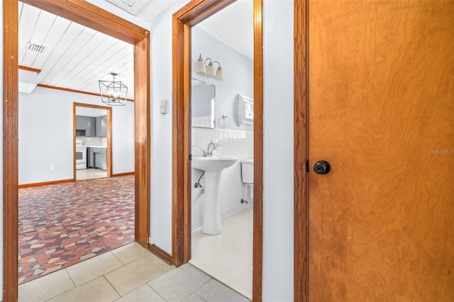 hallway with tile walls and light tile patterned flooring