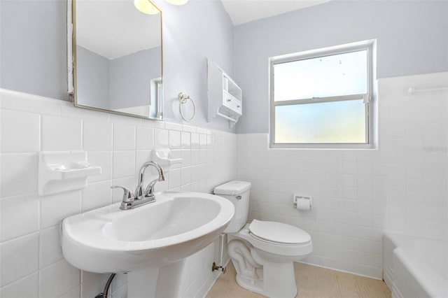 bathroom featuring tile walls, a bathtub, sink, and toilet