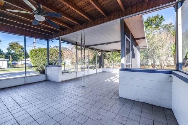 unfurnished sunroom with ceiling fan and beamed ceiling