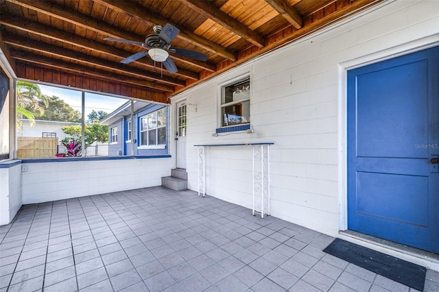 unfurnished sunroom featuring wooden ceiling, ceiling fan, and beam ceiling