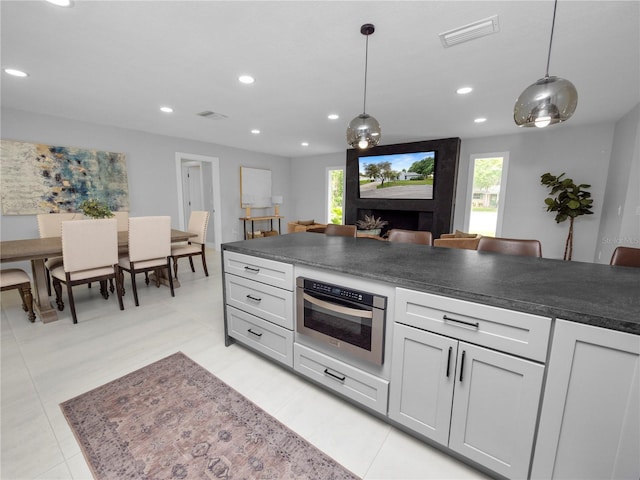 kitchen with oven, decorative light fixtures, a wealth of natural light, and light tile patterned floors