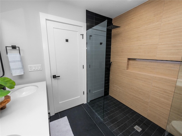 bathroom featuring tile patterned flooring, a tile shower, and vanity