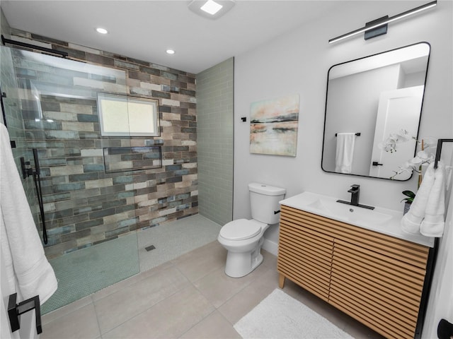 bathroom with toilet, vanity, tile patterned floors, and tiled shower