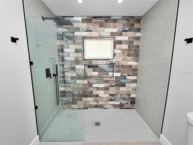 bathroom featuring a tile shower and toilet