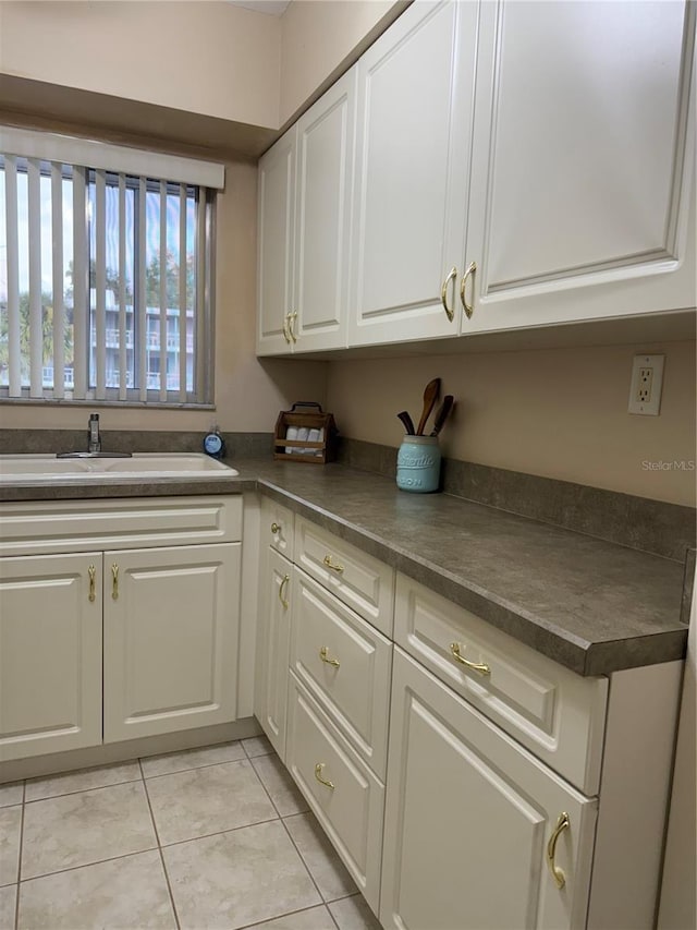 kitchen featuring light tile patterned floors, white cabinets, and sink