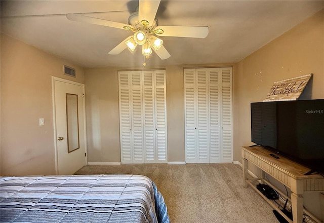 carpeted bedroom featuring ceiling fan and multiple closets