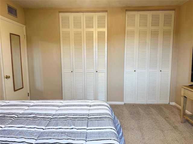 bedroom featuring carpet floors and two closets