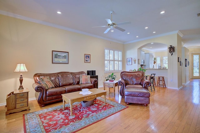 living room with light wood-type flooring, ceiling fan, and ornamental molding