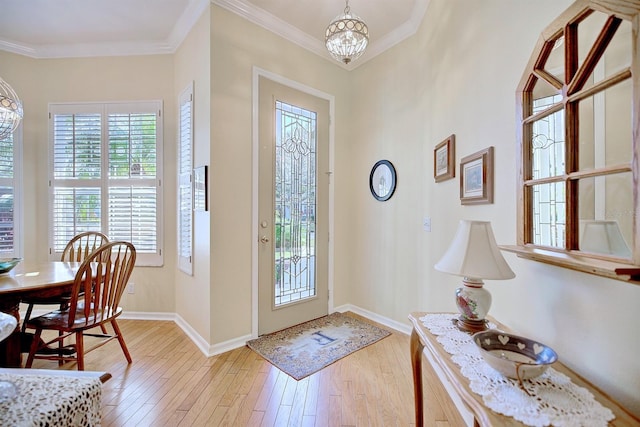 entrance foyer featuring an inviting chandelier, light wood-type flooring, and crown molding