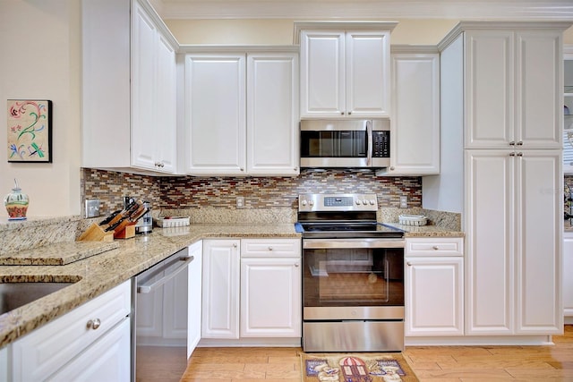 kitchen with stainless steel appliances, light stone countertops, decorative backsplash, white cabinets, and light hardwood / wood-style flooring