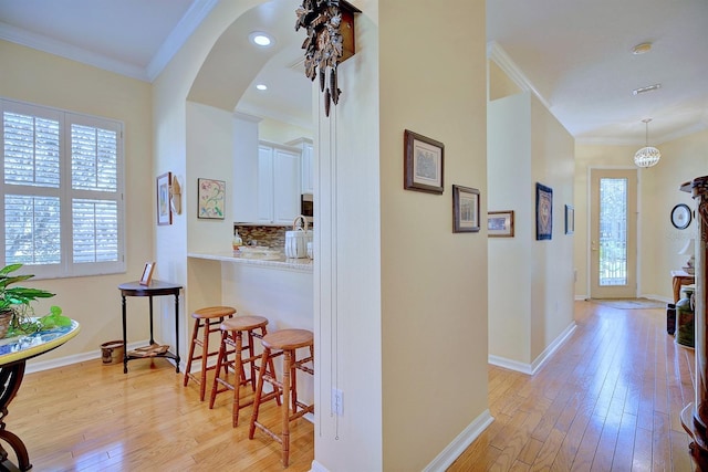 corridor with light hardwood / wood-style floors and crown molding