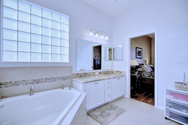 bathroom featuring a relaxing tiled tub, tile patterned floors, and vanity