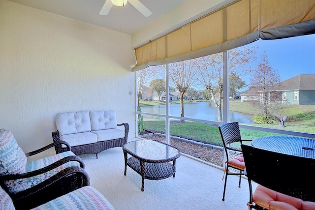 sunroom featuring ceiling fan and a water view