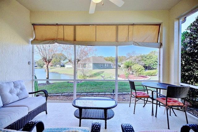 sunroom featuring ceiling fan and a water view