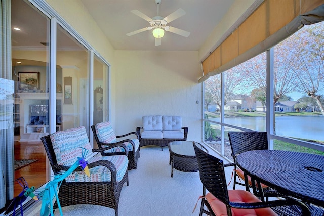 sunroom featuring ceiling fan and a water view