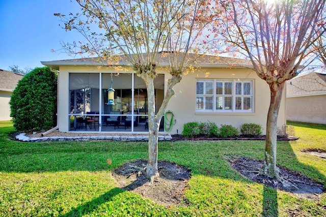 back of property with a lawn and a sunroom