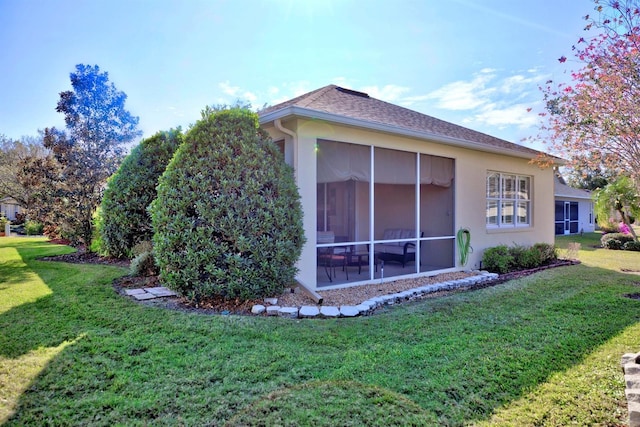 view of home's exterior with a sunroom and a lawn