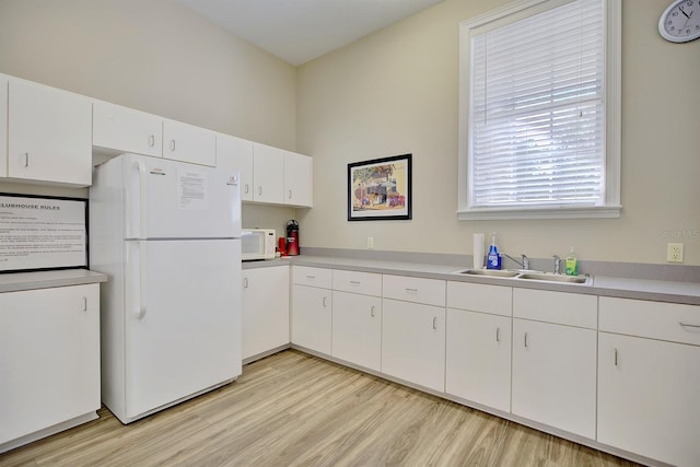 kitchen featuring sink, white appliances, white cabinets, and light hardwood / wood-style flooring