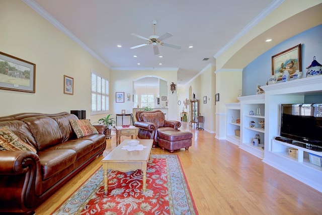 living room with light hardwood / wood-style floors, ceiling fan, built in shelves, and crown molding