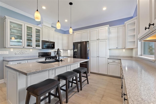 kitchen featuring sink, light wood-type flooring, appliances with stainless steel finishes, and a breakfast bar