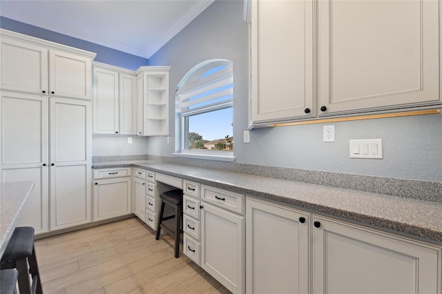 kitchen featuring white cabinets, built in desk, crown molding, and light wood-type flooring