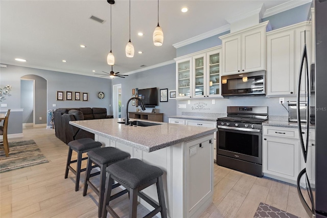 kitchen featuring sink, an island with sink, a breakfast bar area, and stainless steel gas range oven