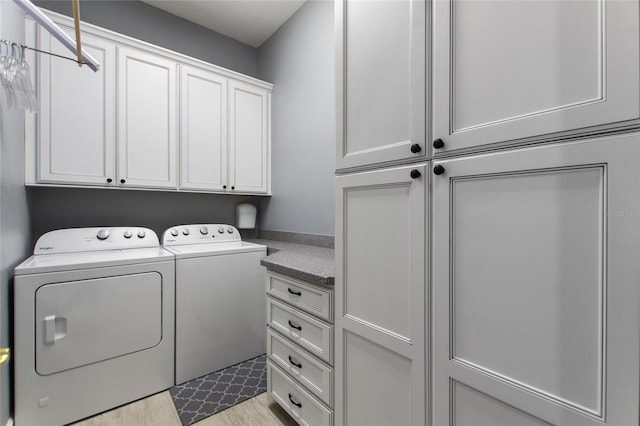 washroom with cabinets, washing machine and dryer, and light hardwood / wood-style floors