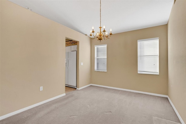 carpeted spare room with an inviting chandelier and plenty of natural light