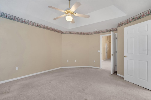 spare room with light carpet, ceiling fan, and a tray ceiling