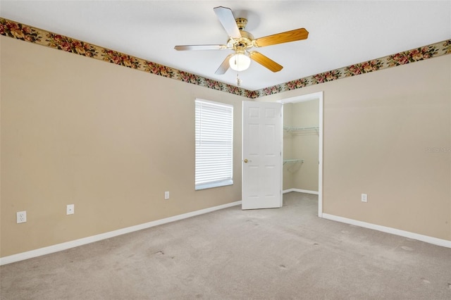 unfurnished bedroom featuring light colored carpet, ceiling fan, a spacious closet, and a closet